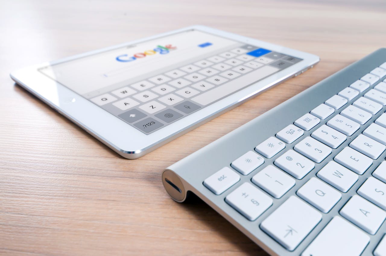 services-img A modern tablet displaying a search engine logo next to a wireless keyboard on a wooden desk.